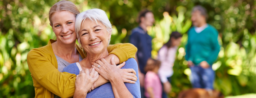 Image of woman hugging mother from behind in a park